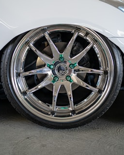 A close-up of a shiny car wheel with a vibrant background.