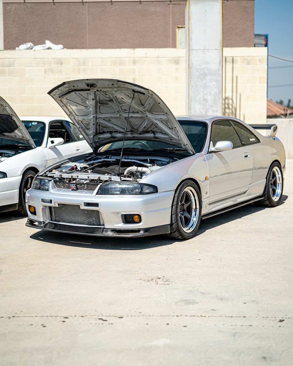 silver bmw m 3 coupe parked beside white concrete building during daytime