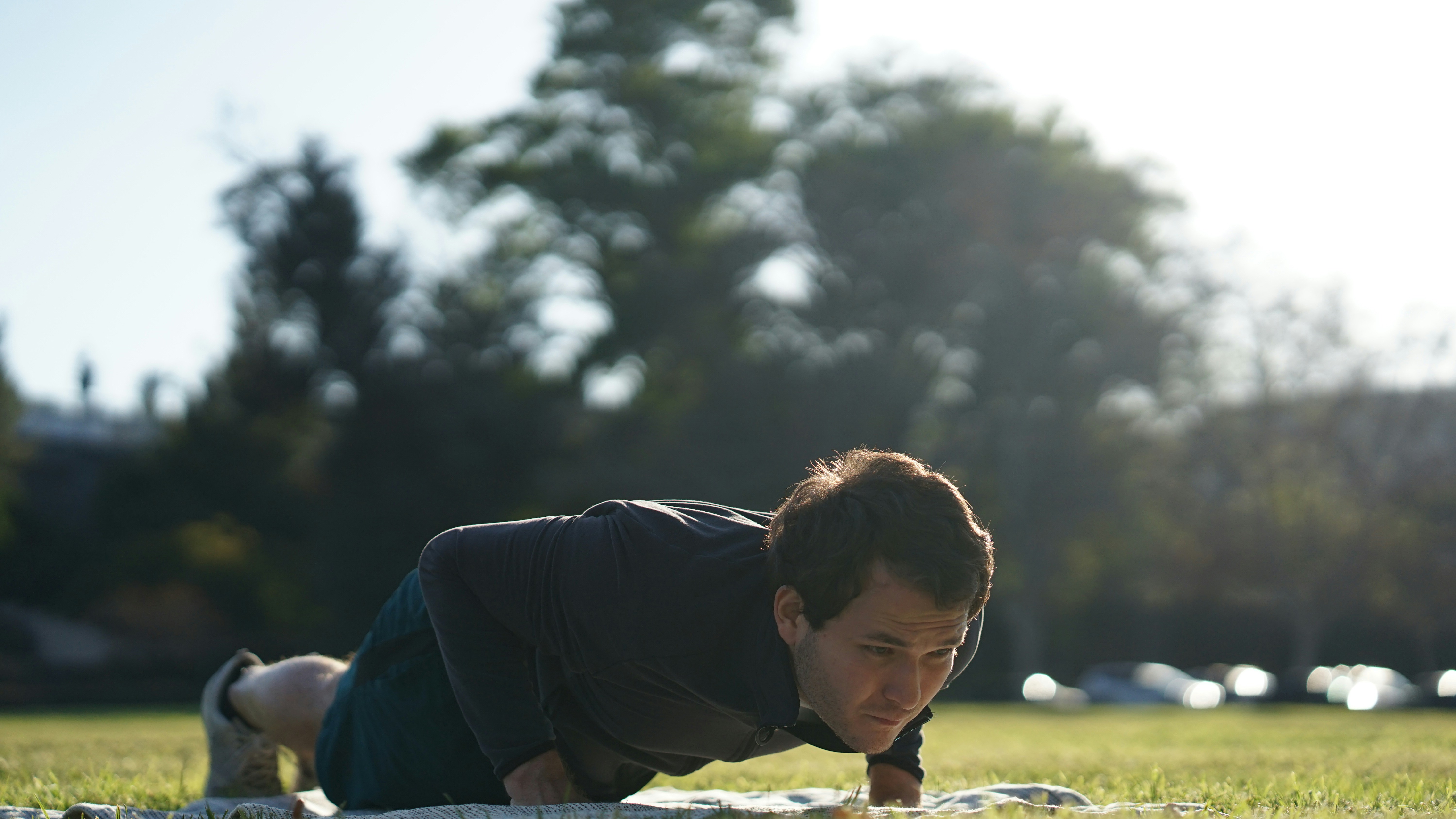 man in black long sleeve shirt sitting on green grass field during daytime
