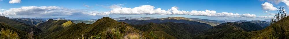 green and brown mountains under white clouds and blue sky during daytime