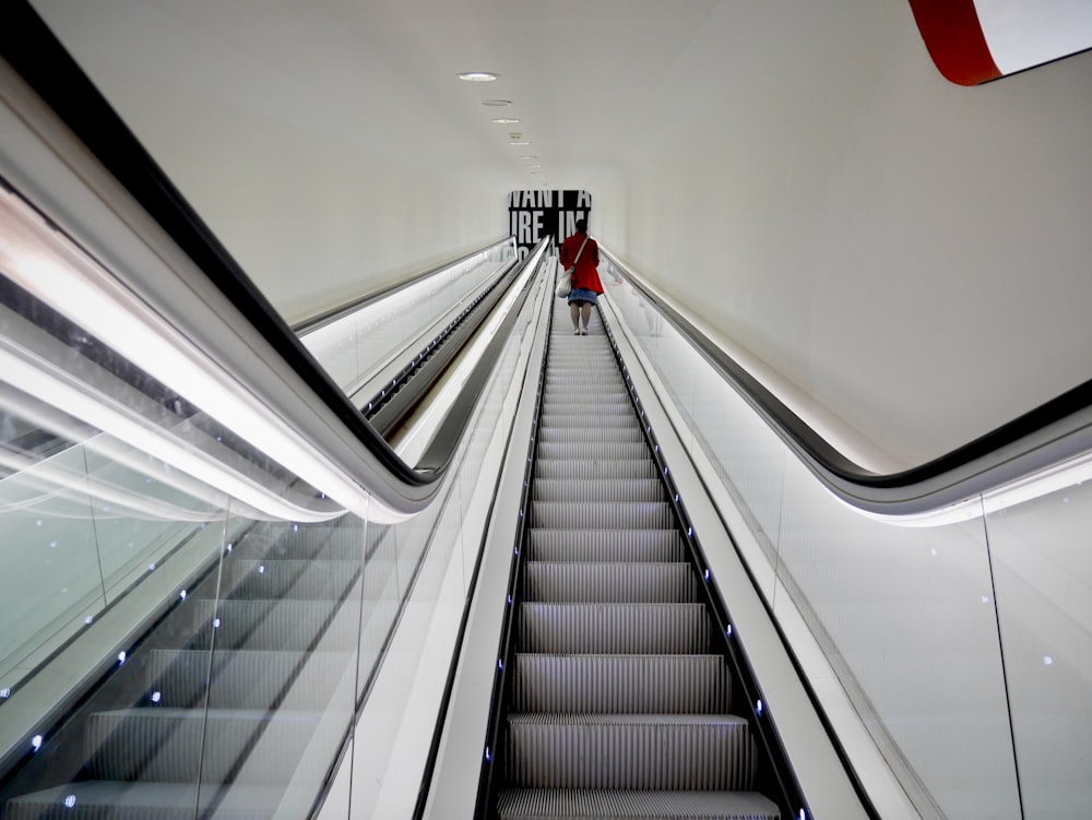 person in red shirt walking on escalator