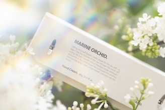 A soothing hand lotion bottle surrounded by fresh flowers.