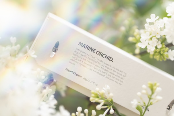 A soothing hand lotion bottle surrounded by fresh flowers.