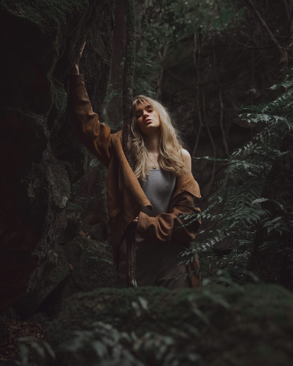 검은 가죽 재킷을 입은 여자가 숲 한가운데에 서 있다