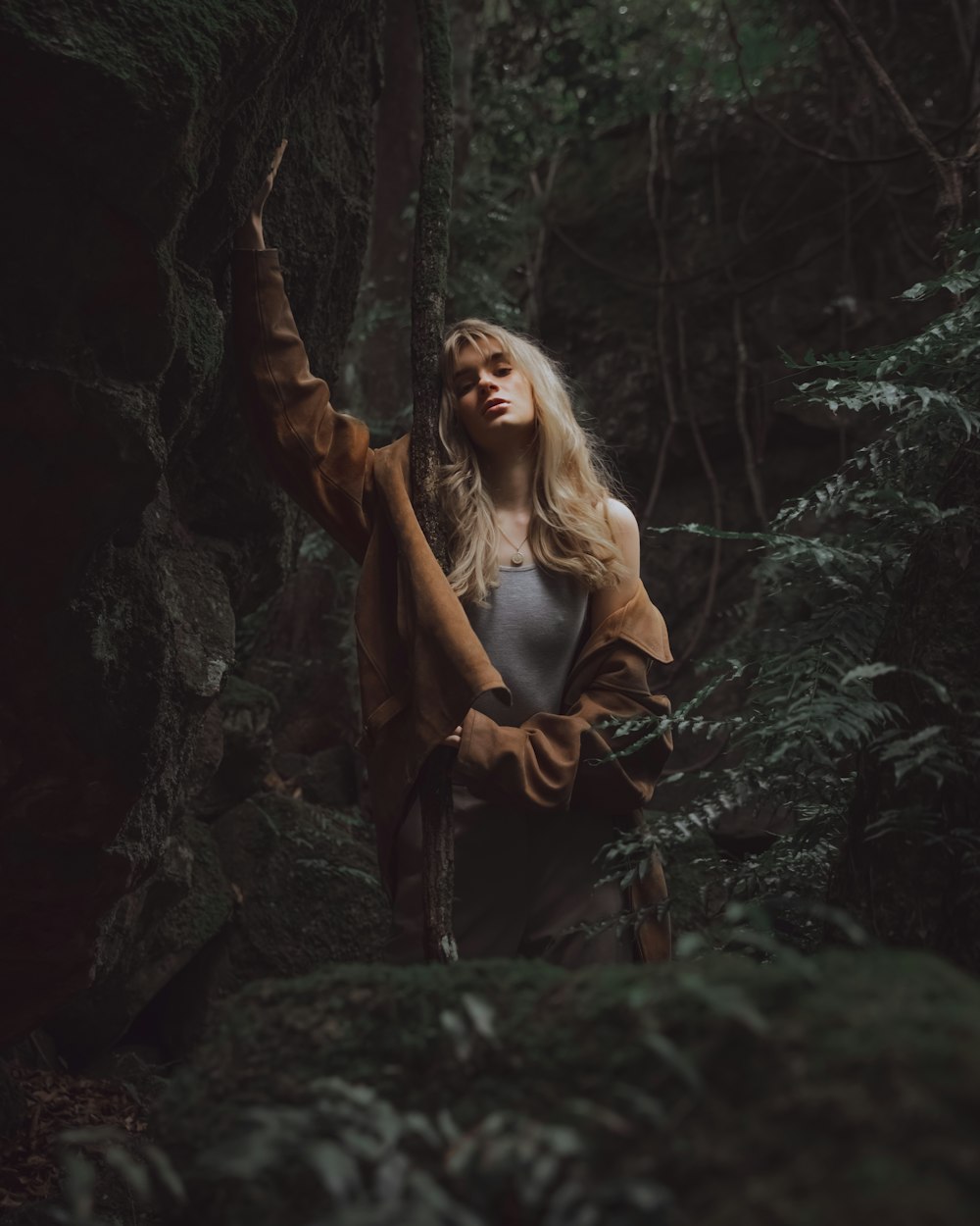 woman in black leather jacket standing in the middle of the woods