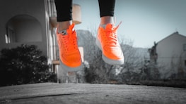 Close-up of running shoes hitting the pavement with orange and white colors