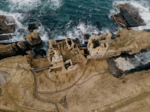A panoramic view of the ruins of a Crusader castle overlooking the Mediterranean coastline.