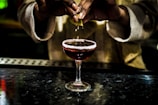 person holding clear wine glass with red liquid