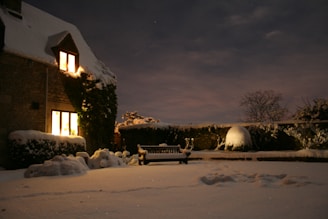A cozy home with a Heaton heat pump quietly working outside during a snowy evening.