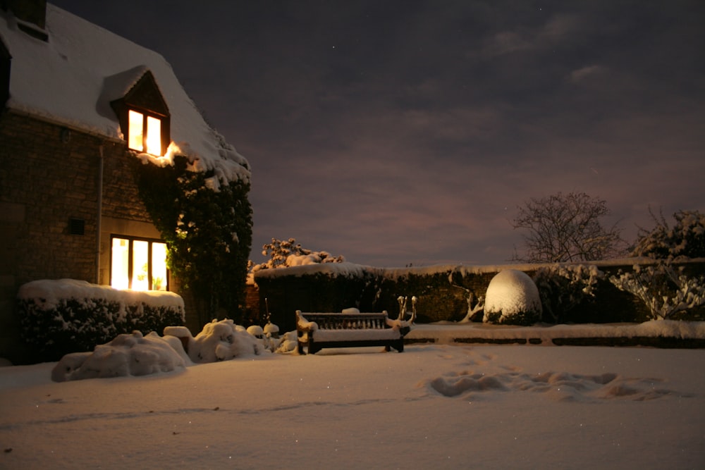 a bench in the snow in front of a house