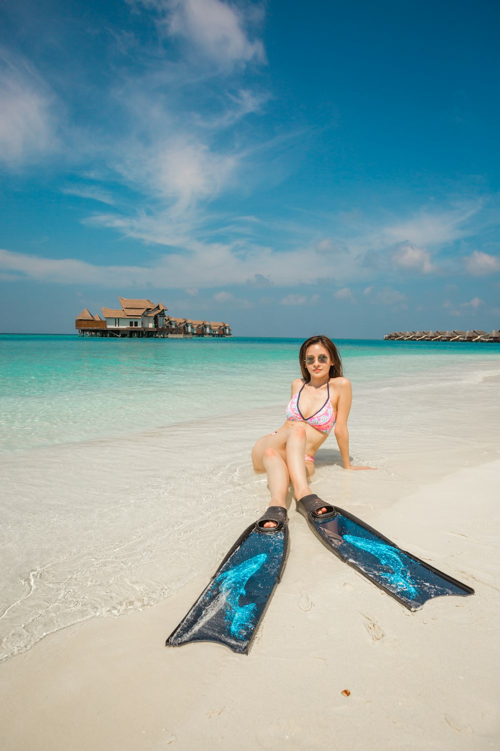 a woman in a bikini sitting on a surfboard on the beach