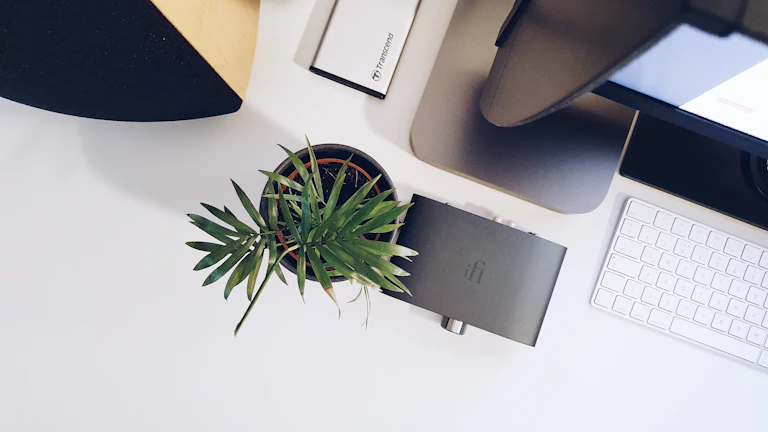 Minimalist workspace featuring an echovibe speaker beside a laptop, ready to boost productivity with music.