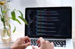 person using macbook pro on white table