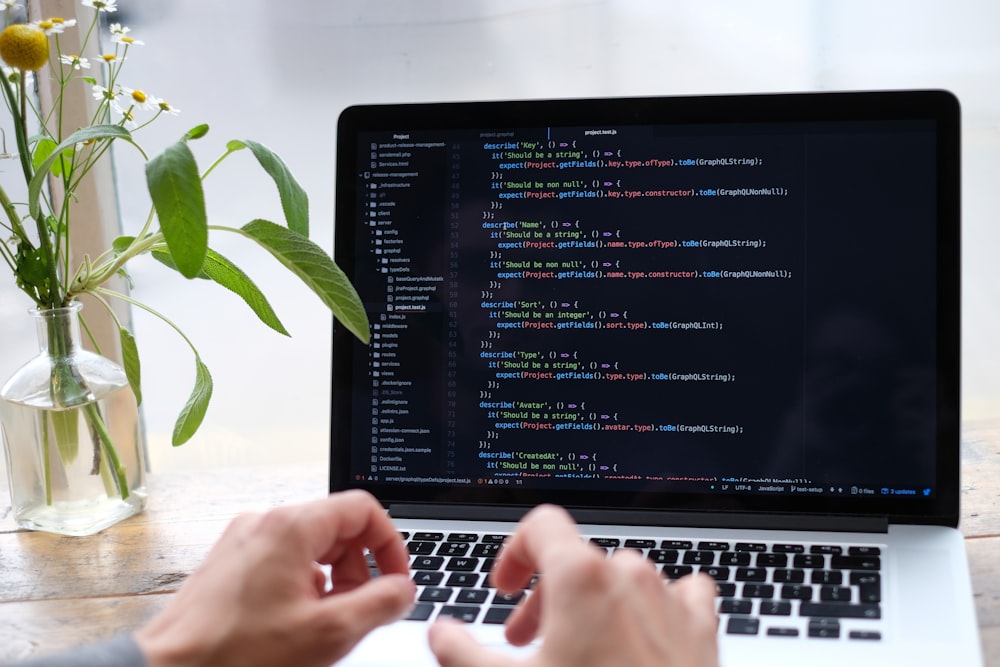 person using macbook pro on white table