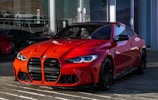 red bmw m 3 coupe parked in front of a tire shop 