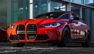 red bmw m 3 coupe parked in front of white building