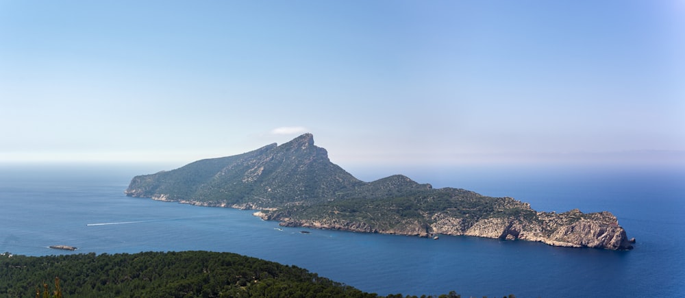 green mountain beside body of water during daytime