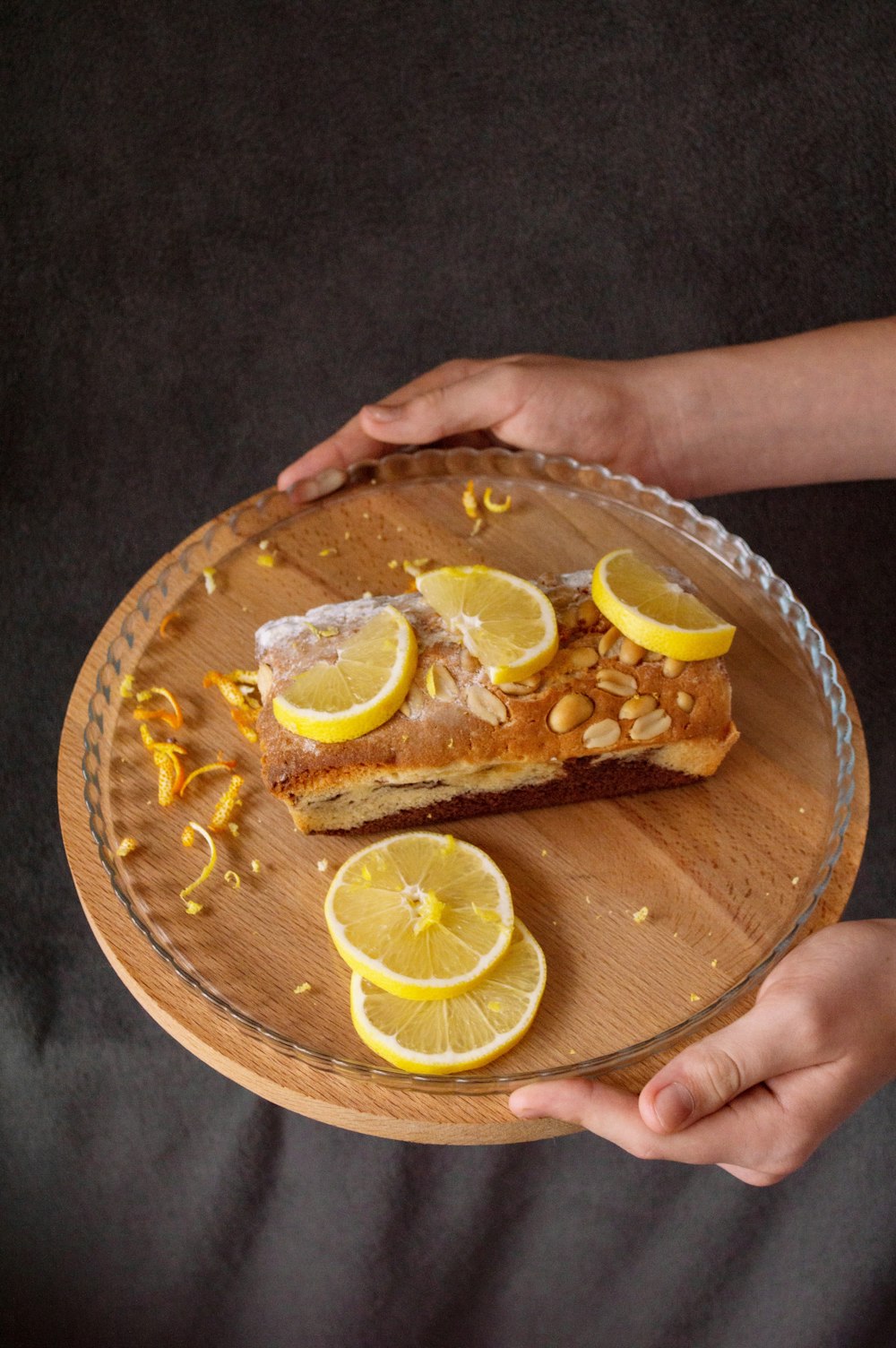 person holding brown wooden tray with sliced lemon