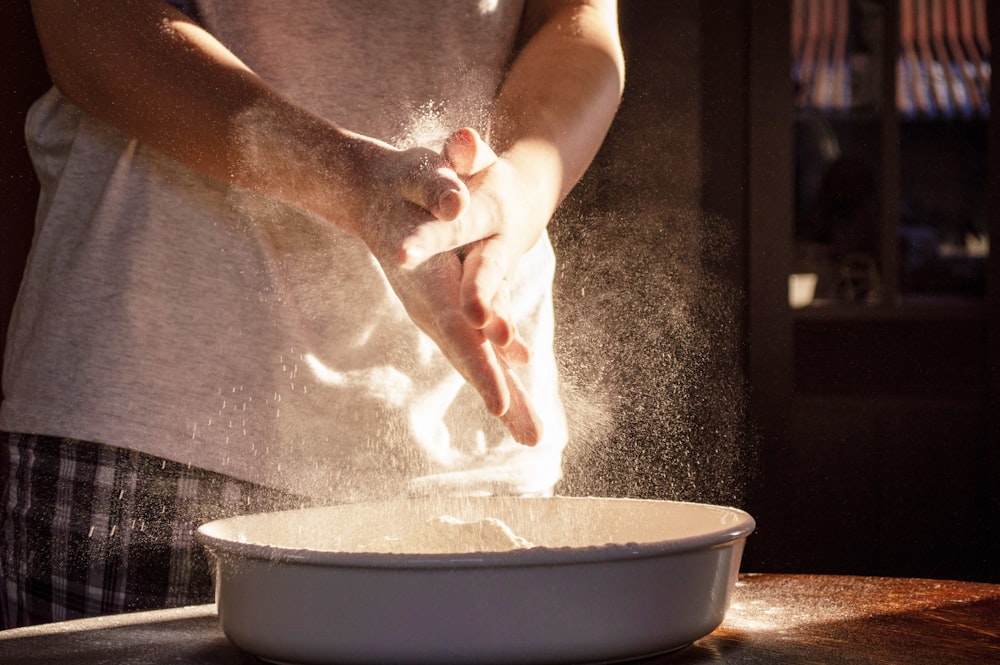 person pouring water on round brown plastic basin