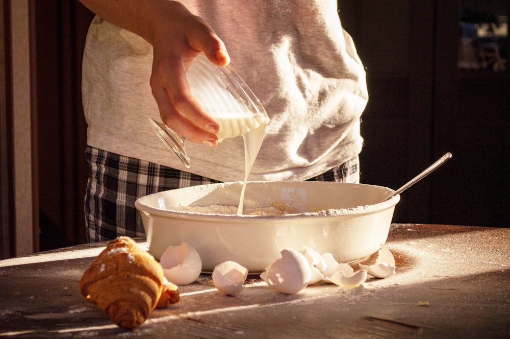 person holding white ceramic bowl with brown liquid