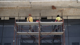 man in yellow jacket standing on red metal ladder