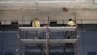 man in yellow jacket standing on red metal ladder