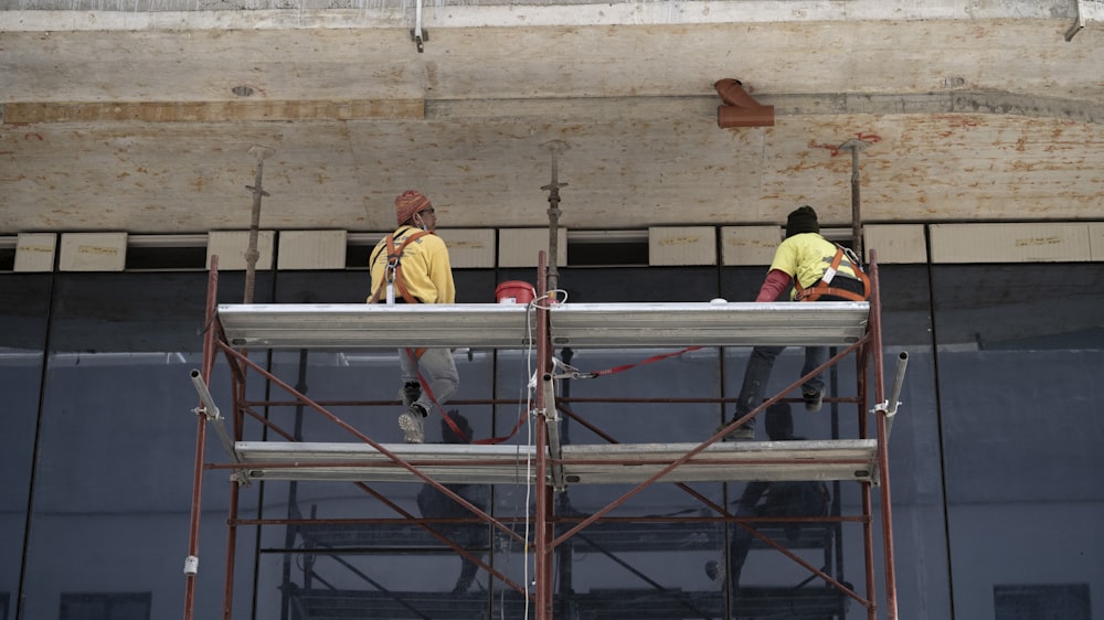 man in yellow jacket standing on red metal ladder