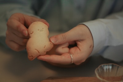 A smiling baker holding a giant cookie, with a rustic wooden table and baking tools in the background.
