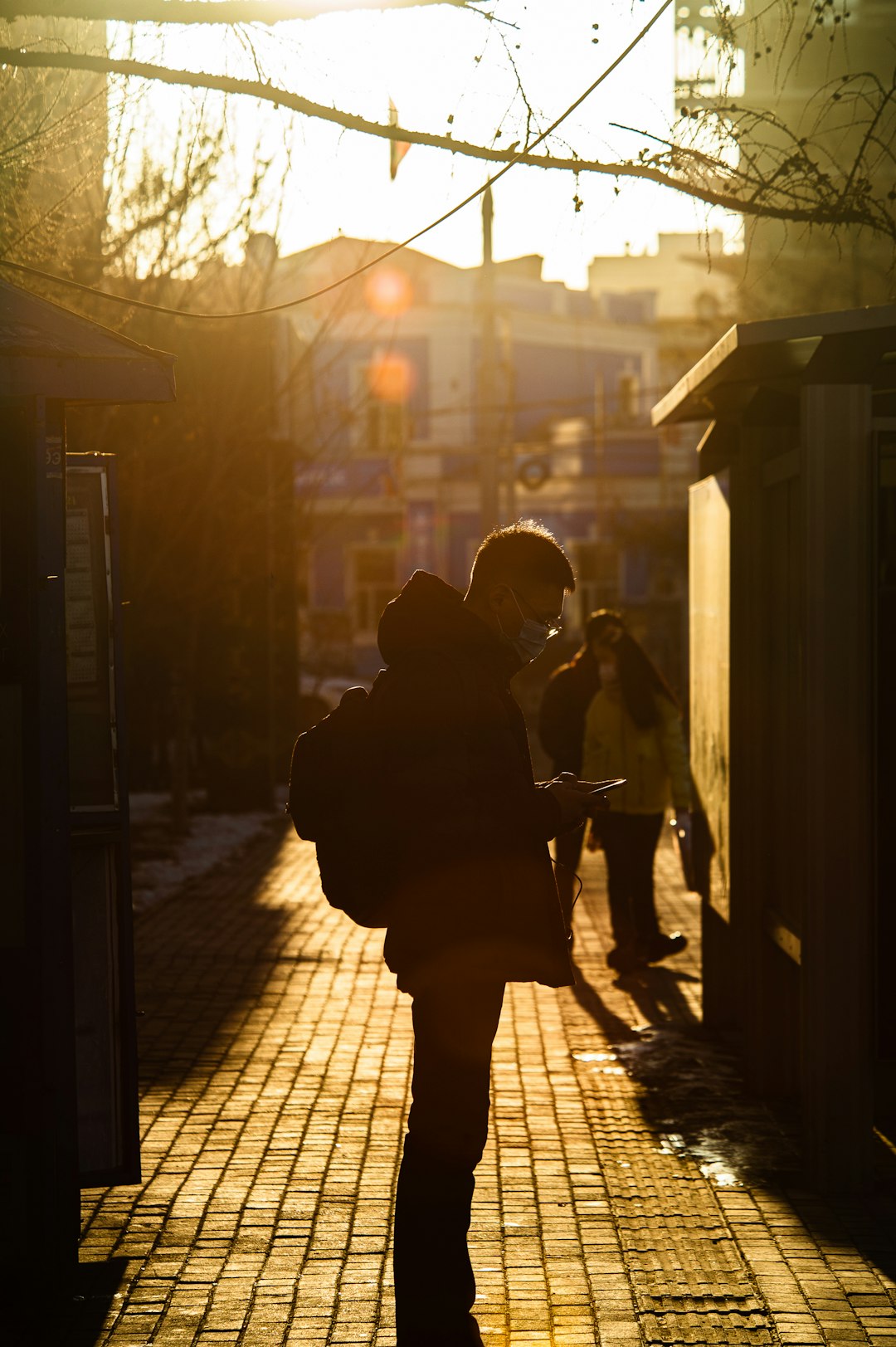 man in black jacket standing beside building during night time