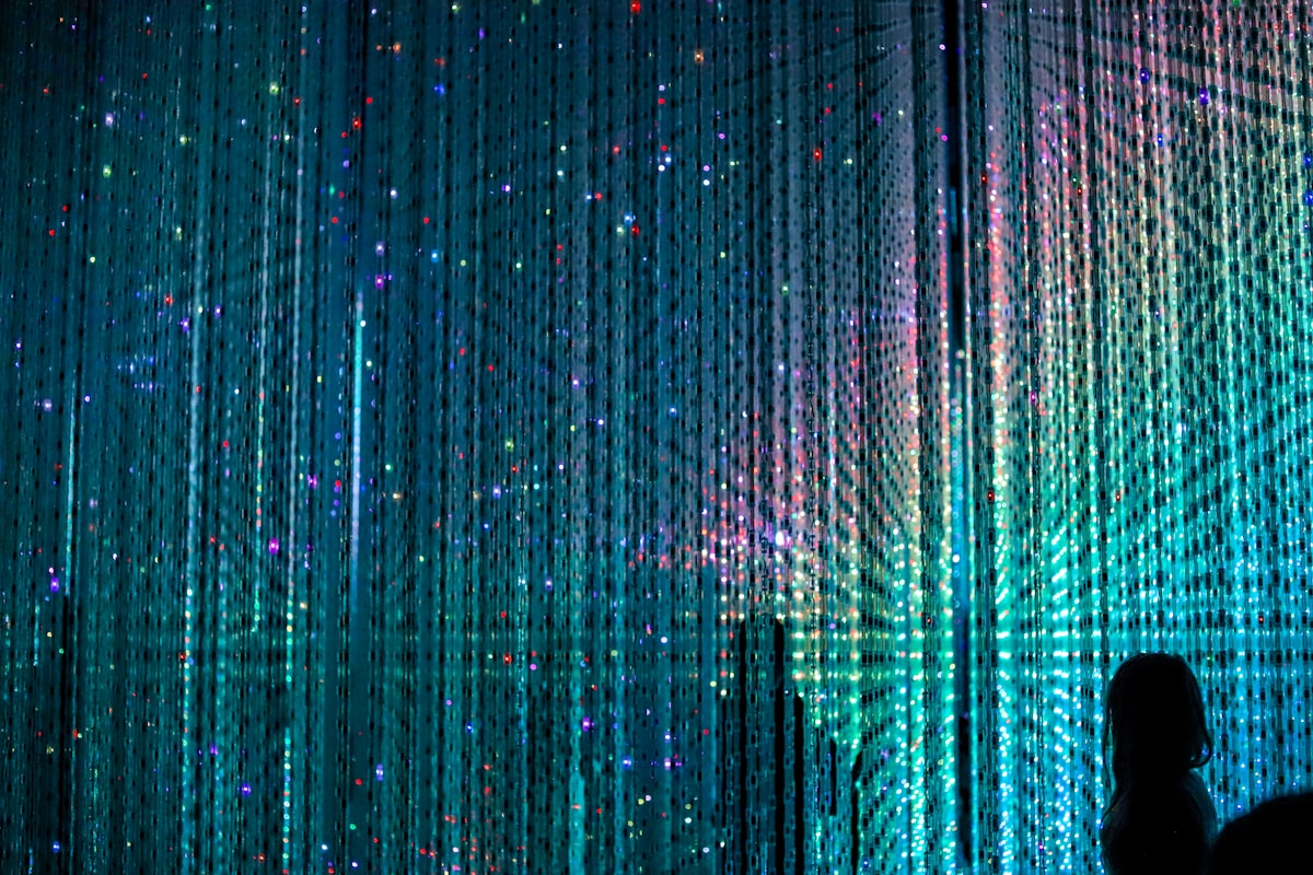 Visitors wading through shallow water surrounded by digital reflections at TeamLab Planets Tokyo