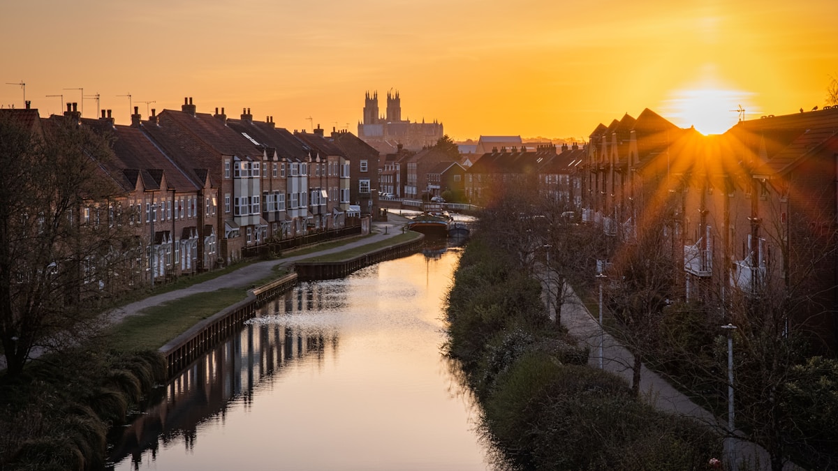 body of water between houses during sunset