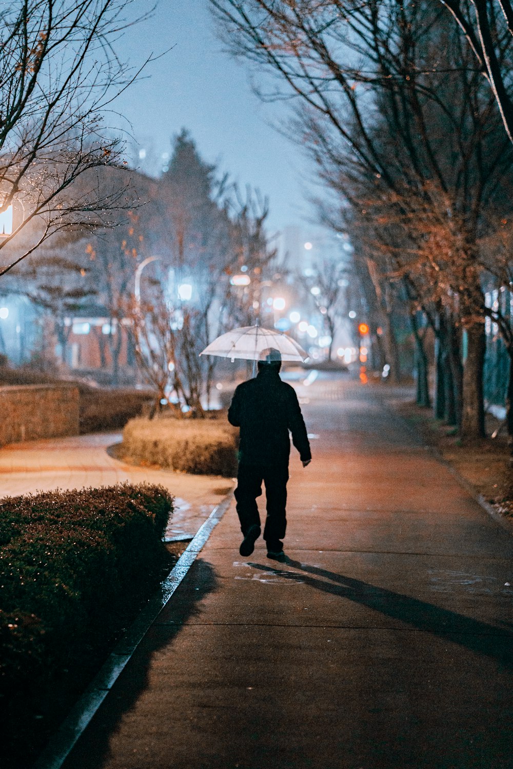 personne en manteau noir marchant sur le trottoir pendant la journée