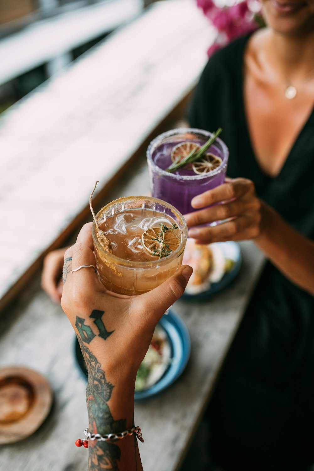 person holding clear drinking glass with brown liquid