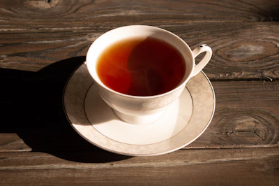 Elegant porcelain cup filled with steaming black tea on a rustic wooden table