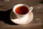 Close-up of a rustic handcrafted porcelain tea cup filled with steaming tea on a wooden table.