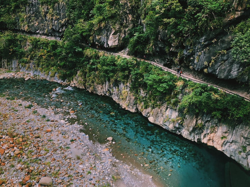 green and gray rocky mountain beside body of water during daytime