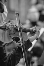 person playing violin in grayscale photography