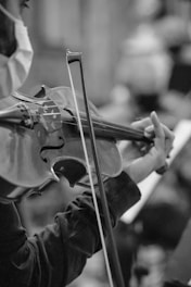 person playing violin in grayscale photography