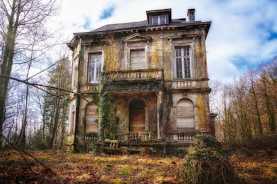 An abandoned, decrepit mansion with broken windows and creeping vines.