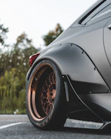 Aggressive stance shot of a modified wheel and low-profile tire on a matte black car.