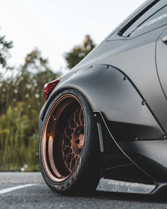Close-up of a modified car wheel with aggressive stance in a high-contrast setting.