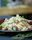 Close-up of homemade pasta being served on a cream-colored plate with soft beige background.