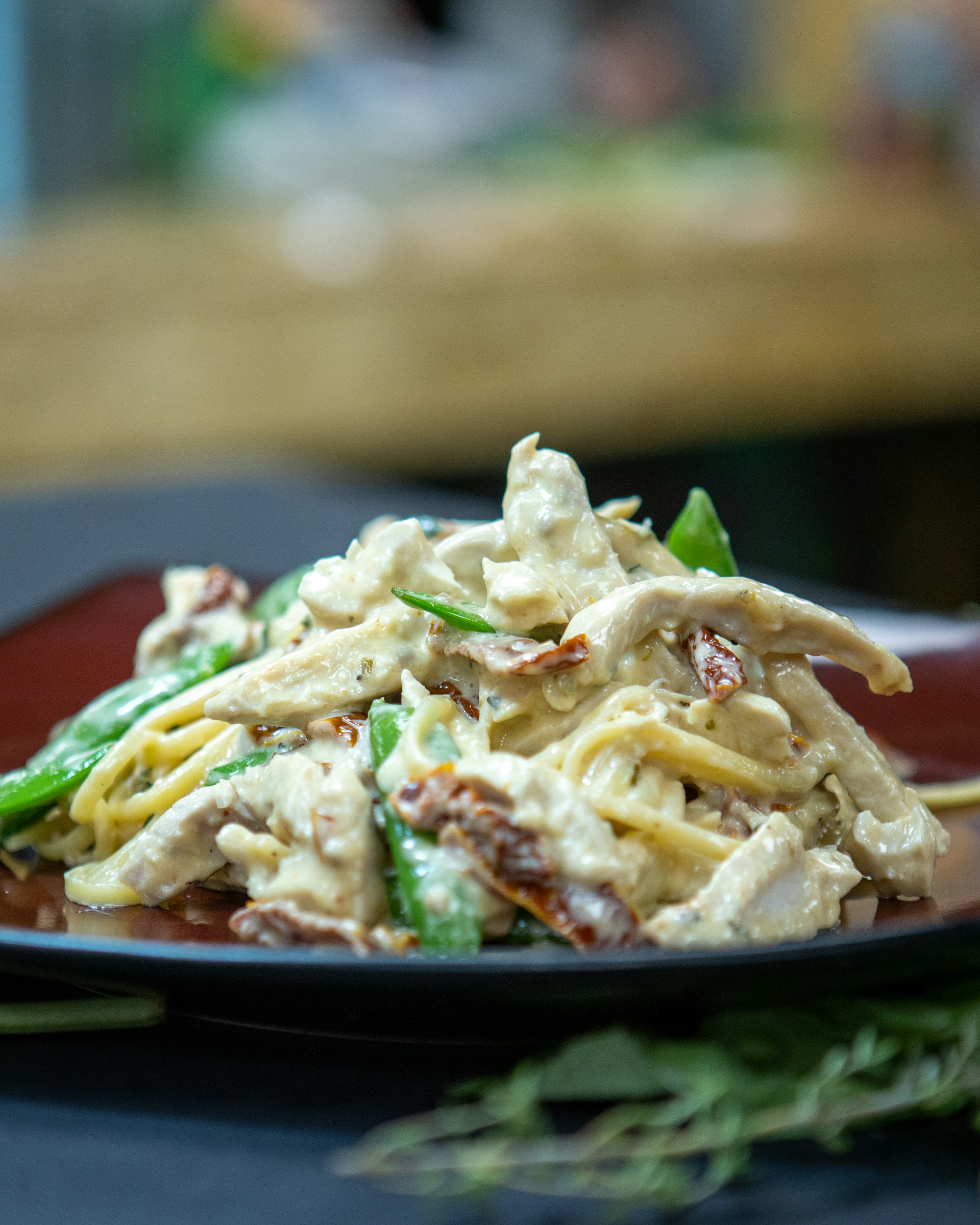 A close-up of a homemade pasta dish on a beige ceramic plate, with fresh herbs sprinkled on top and warm kitchen light casting gentle shadows.