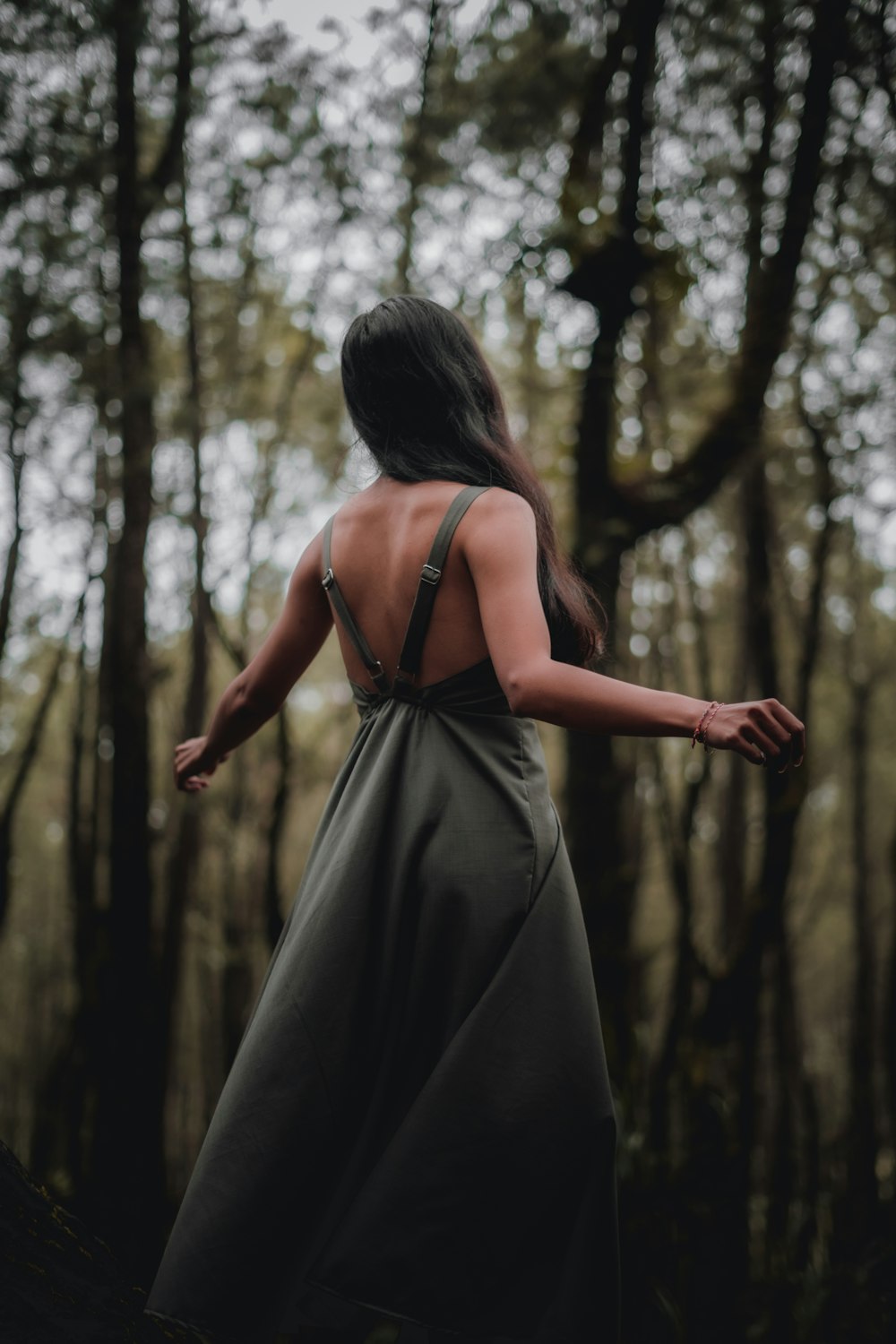 woman in black spaghetti strap dress standing in forest during daytime