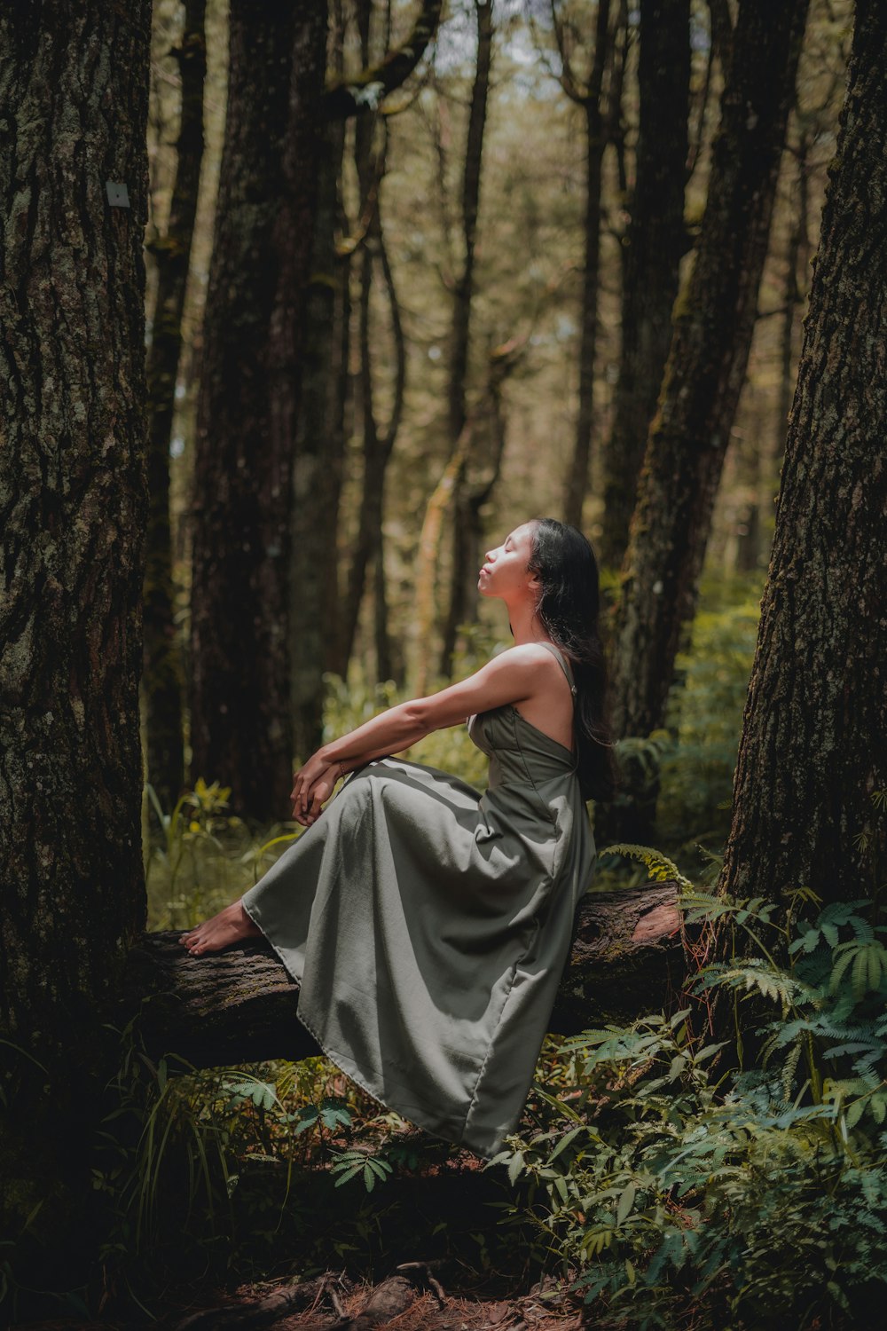 donna in vestito nero seduta a terra circondata da alberi