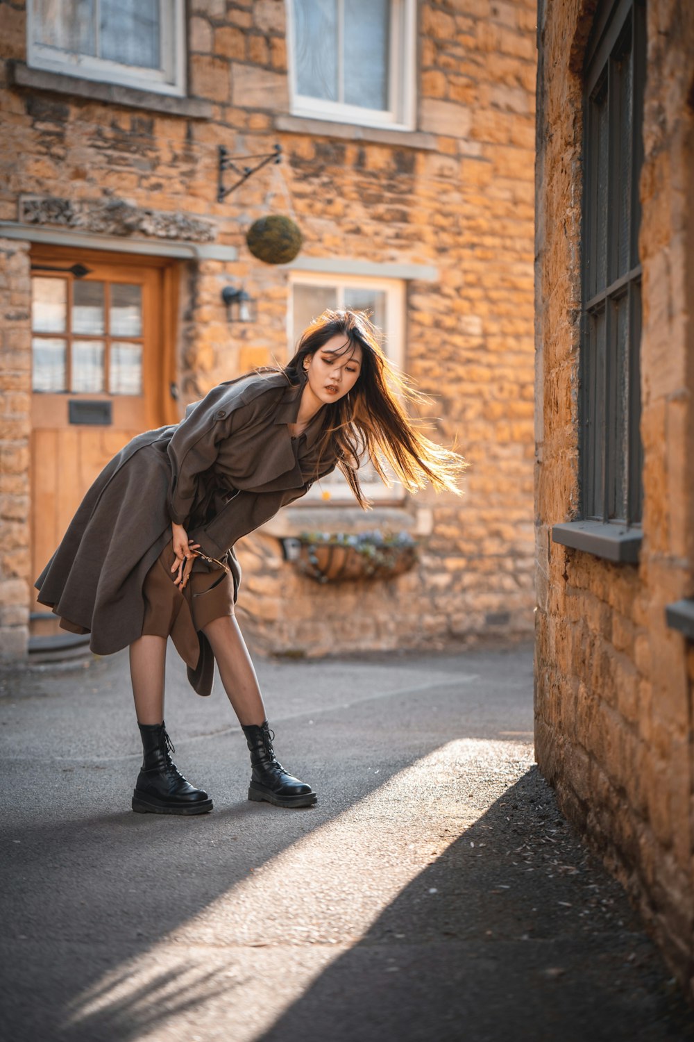 woman in black leather jacket and black skirt standing on sidewalk during daytime