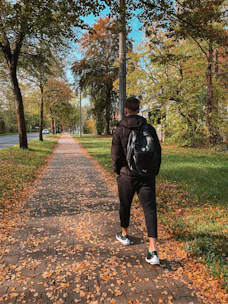 A sturdy backpack leaf blower in action, blowing colorful autumn leaves in a suburban yard.