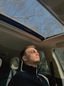 A person enjoying music while driving on a sunny day.