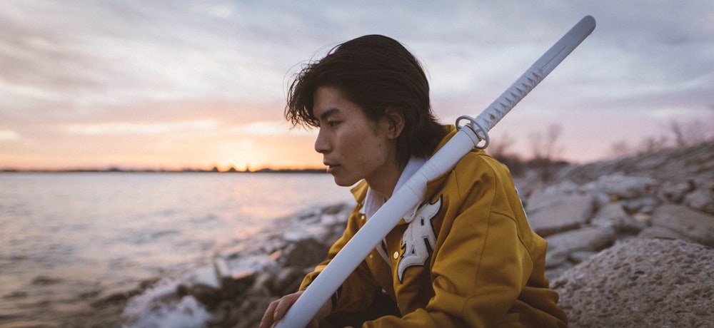 woman in yellow jacket standing on rocky shore during daytime