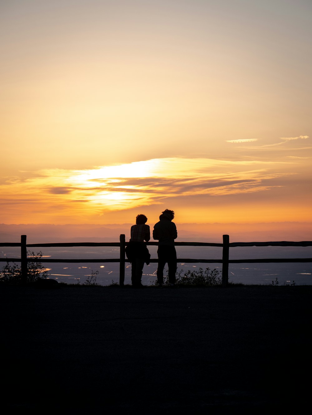 silhouette of 2 person standing on seashore during sunset